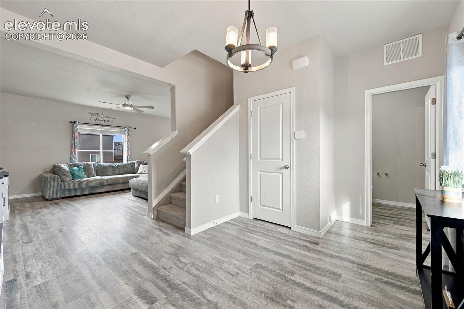 Interior space featuring wood-finish flooring, a multi-arm chandelier with a metal finish, carpeted staircase, and two-panel interior doors