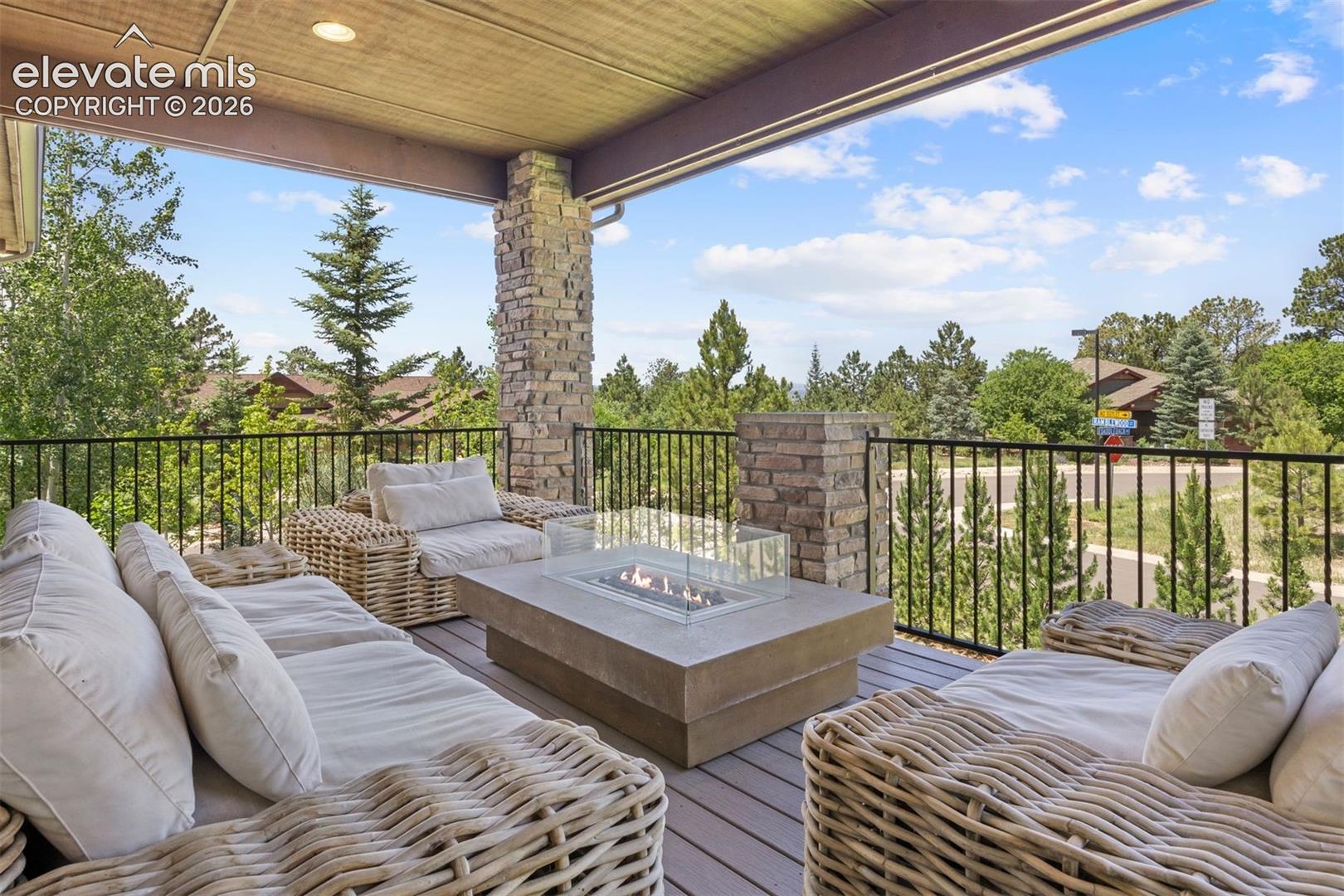 Covered outdoor deck featuring stone-clad pillars and a built-in fire pit