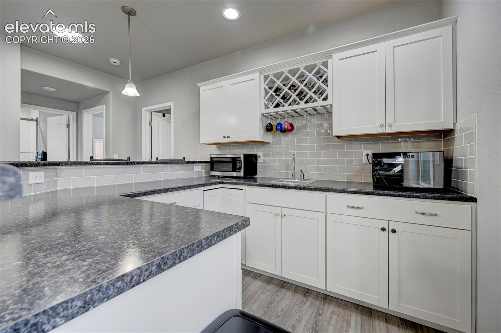 Contemporary kitchen with white shaker-style cabinetry, granite-patterned countertops, and a gray subway tile backsplash