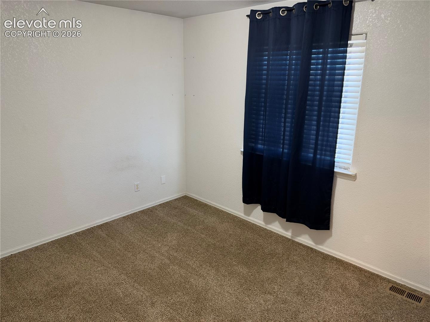 Neutral-toned carpeting, textured wall finish, and a window featuring horizontal blinds