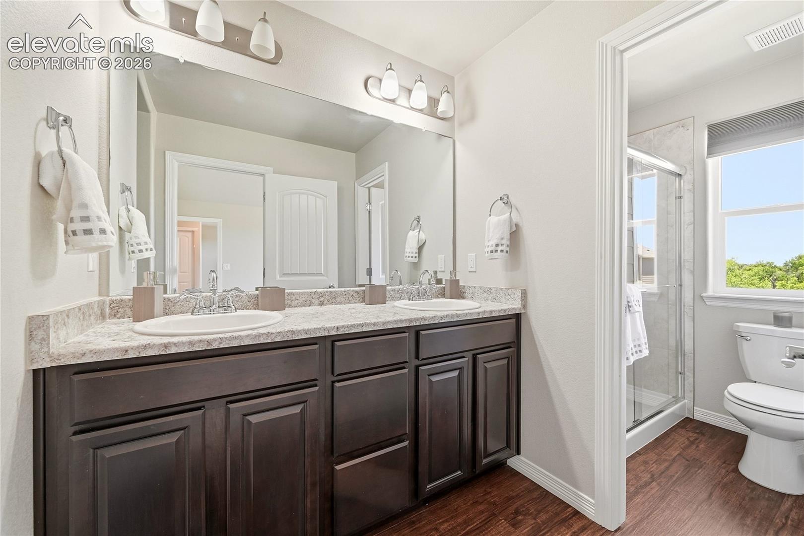 Double vanity featuring dark wood cabinetry, white oval sinks, and a speckled countertop