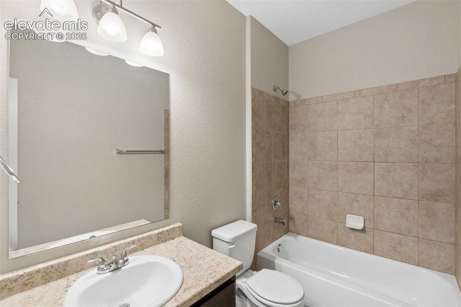 Main Level Bathroom featuring a vanity with a speckled countertop, integrated sink, and an expansive wall mirror
