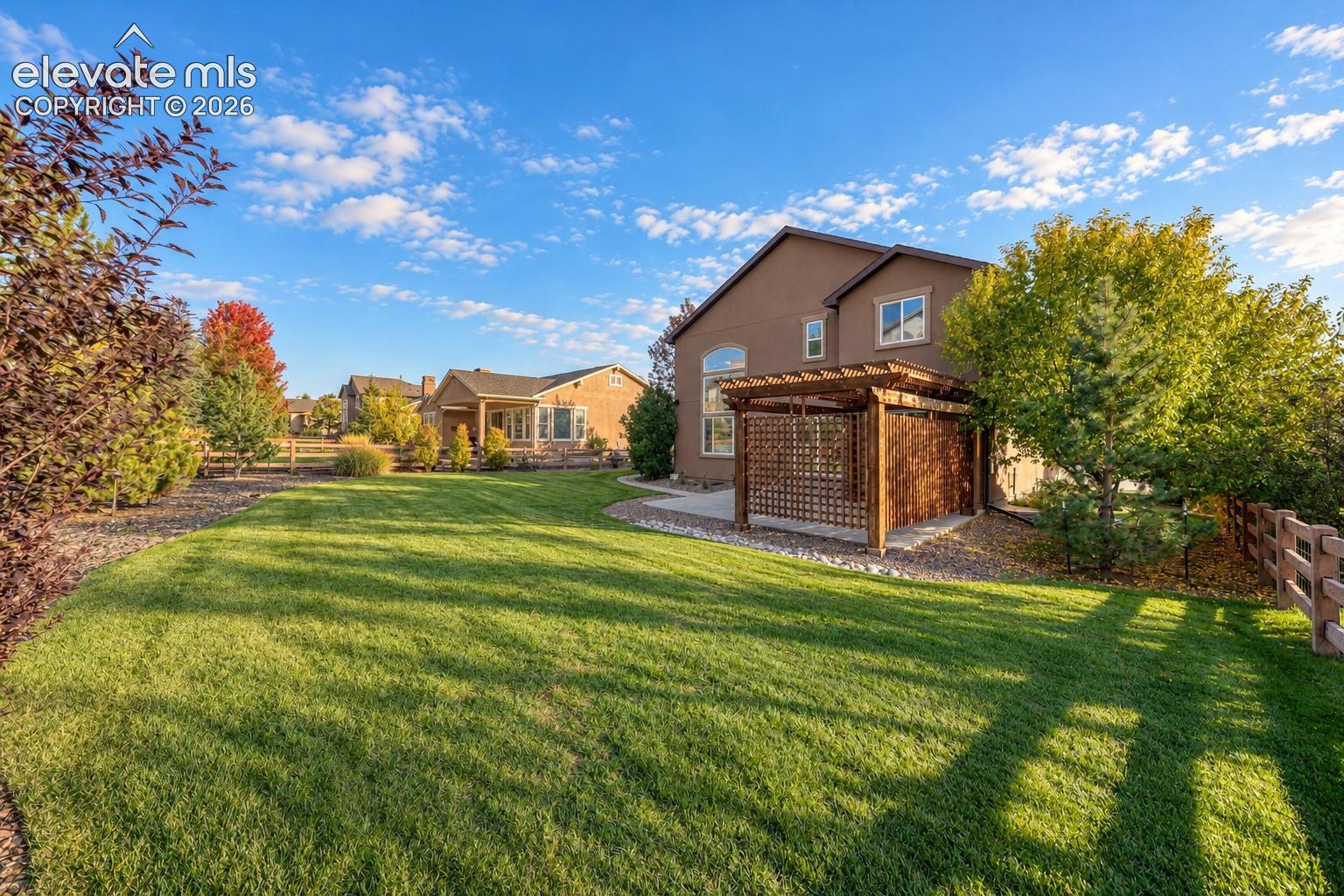 Expansive lawn with mature trees and a wood pergola structure