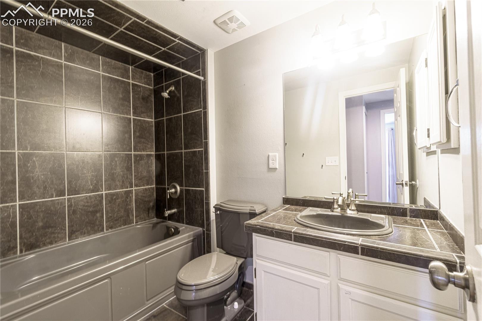 Bathroom with toilet, vanity, shower / washtub combination, and visible vents