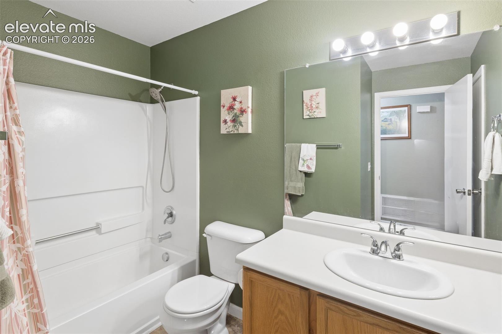 Full bathroom featuring a single vanity with wood-finish cabinetry, a white countertop, and an integrated white sink