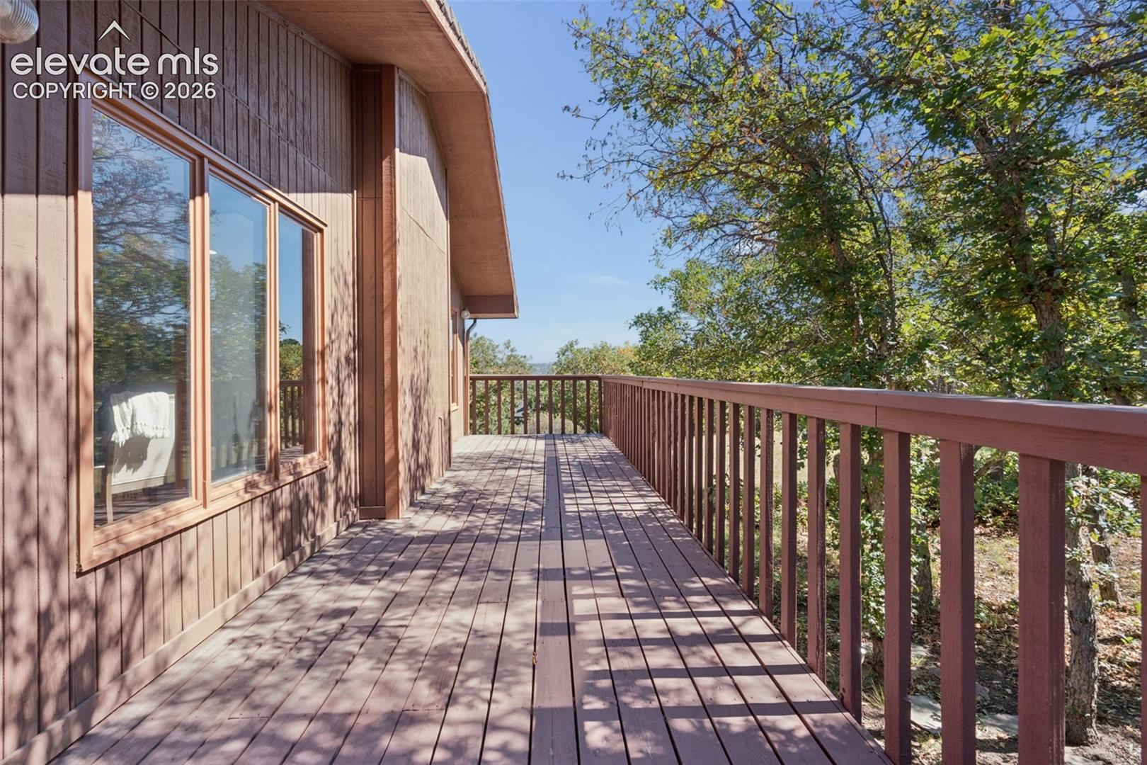 Expansive wood deck with a full-length railing, integrated into the vertical wood-paneled exterior