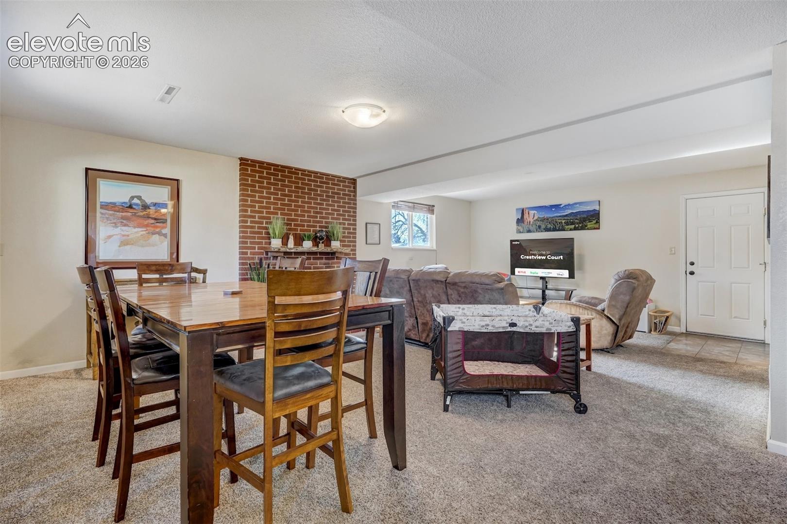 Carpeted living area with a brick accent wall and a window