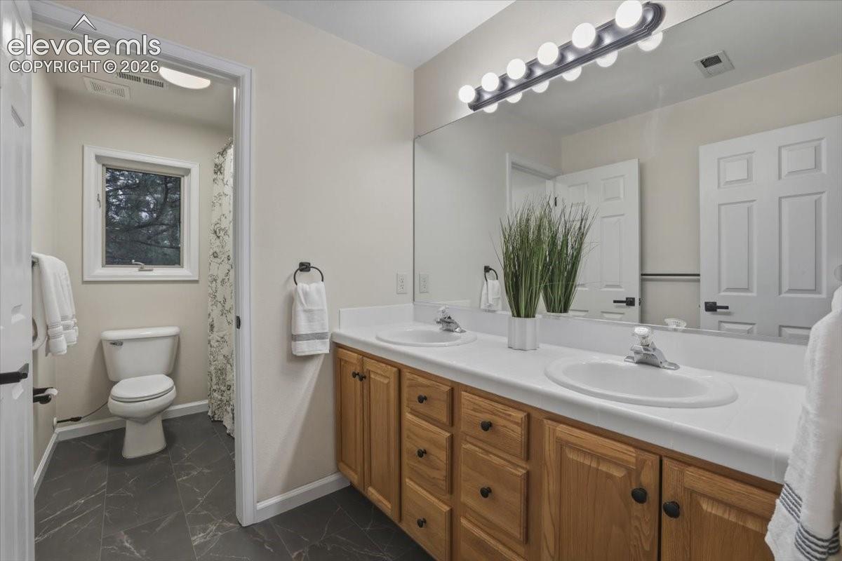 Double vanity with integrated sinks, wood-finish cabinetry, and a full-width mirror