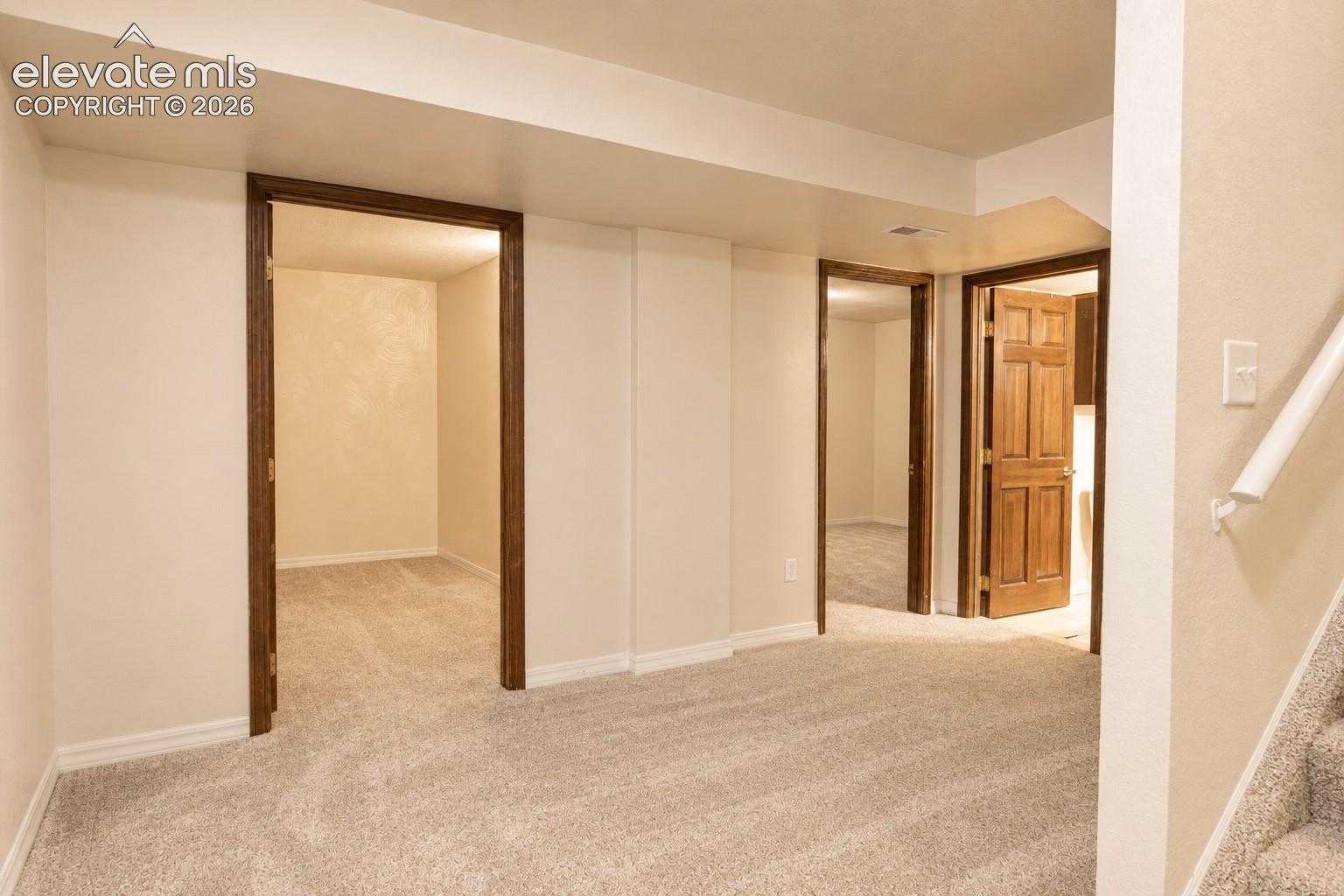 Plush carpet flooring throughout, cream-colored walls, wood-finish door frames, and solid wood interior doors