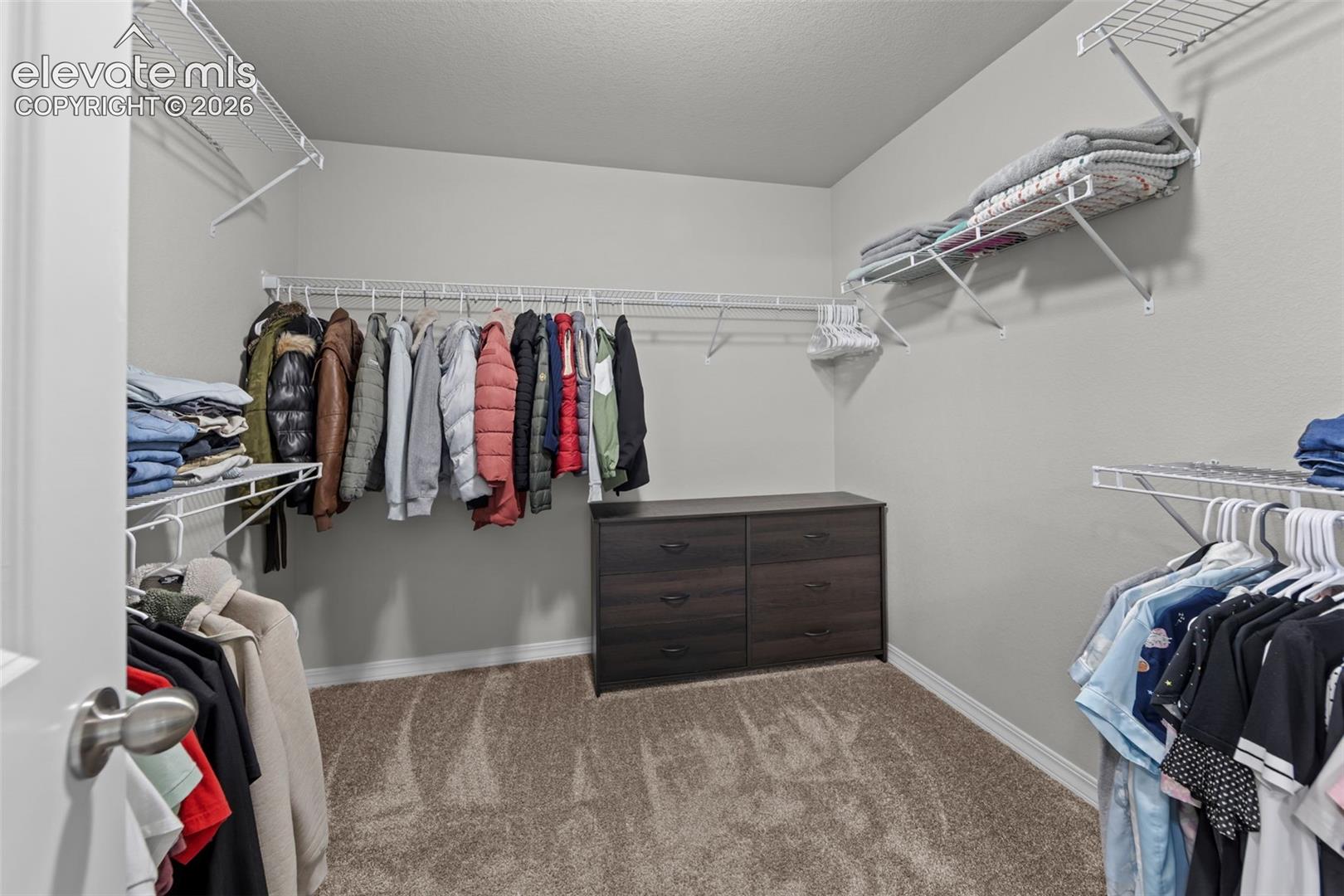 Walk-in closet featuring wire shelving, hanging rods, and a built-in wood-finish dresser