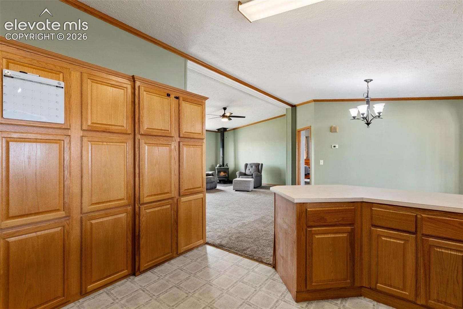Kitchen featuring extensive wood cabinetry, L-shaped countertop, recessed ceiling light, and patterned floor tiles