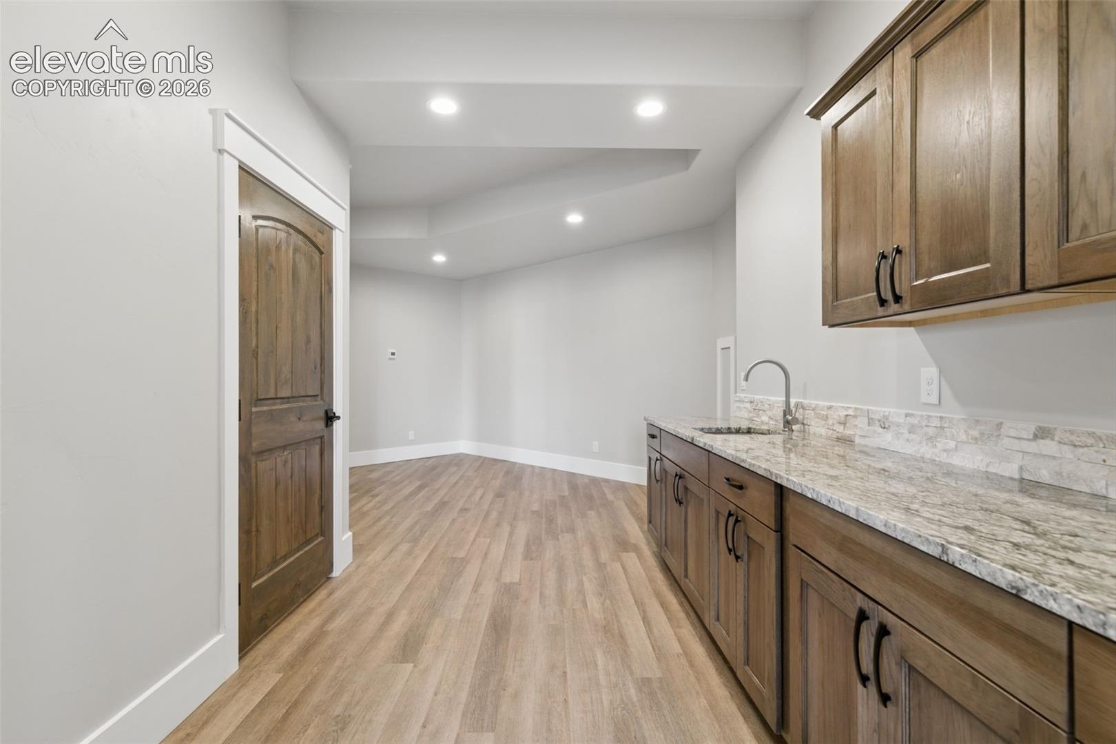 Wood-finish flooring throughout, featuring recessed lighting and a built-in wet bar