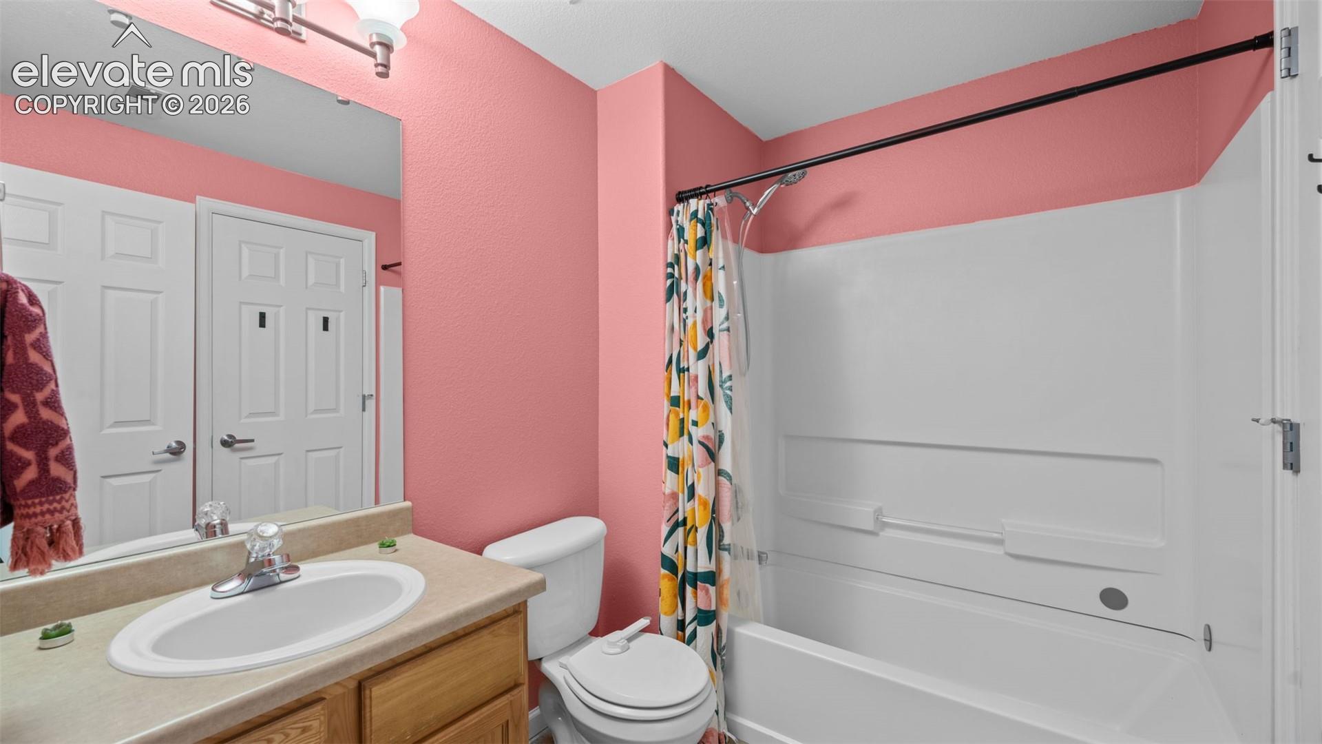 Bathroom featuring a single vanity with a laminate countertop, white oval sink, and chrome faucet