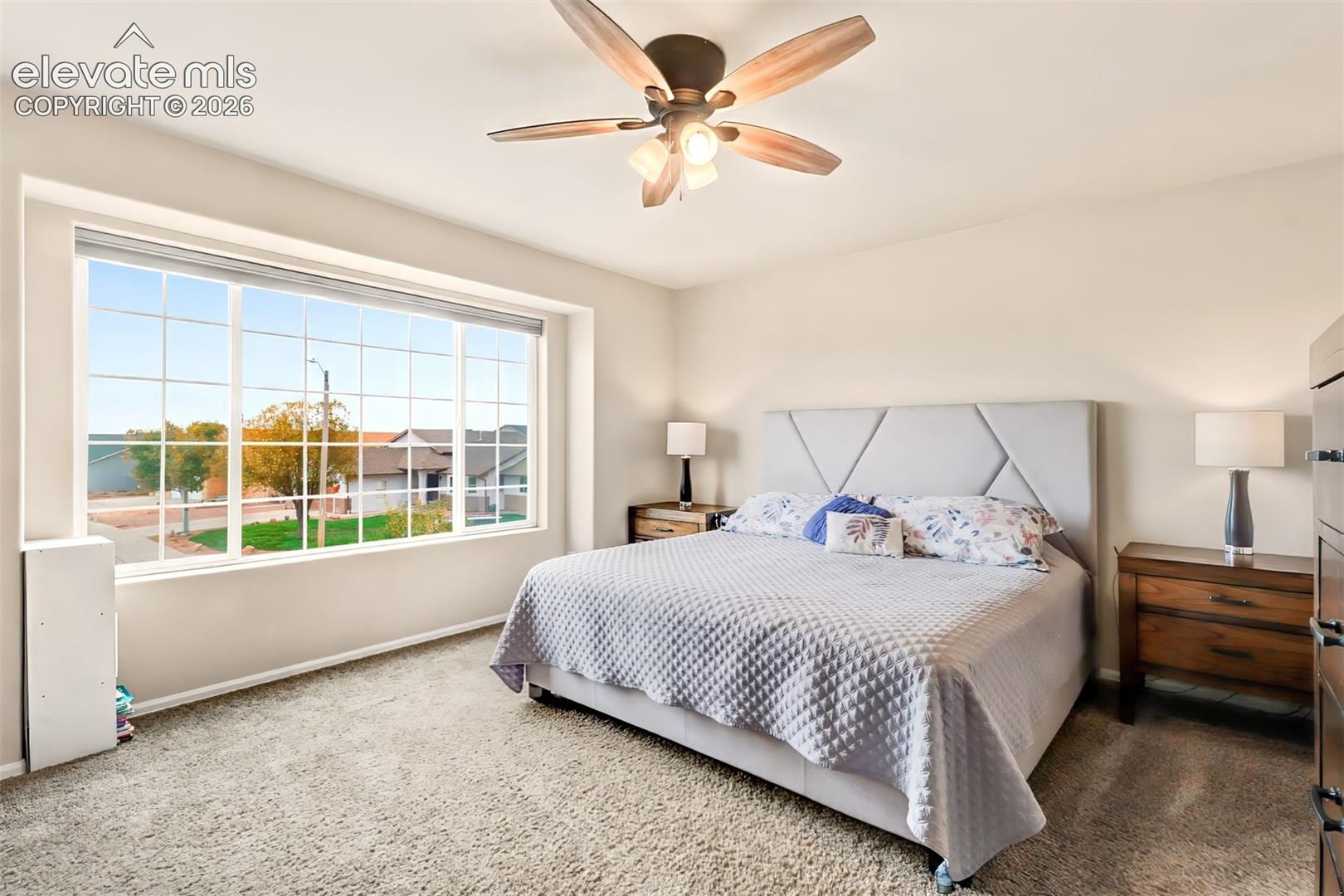 Large picture window with pane dividers, neutral wall color, and a ceiling fan with light fixture
