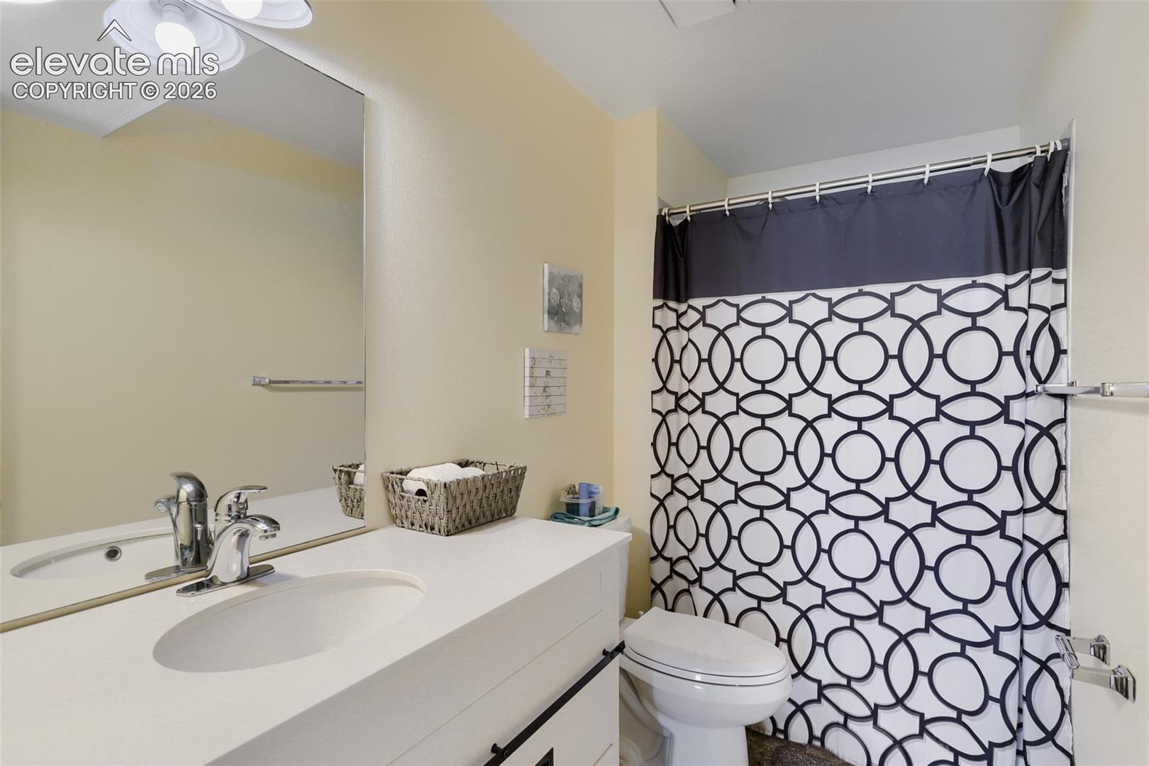 Bathroom featuring a vanity with an integrated sink and chrome faucet, a rectangular wall-mounted mirror, and a toilet