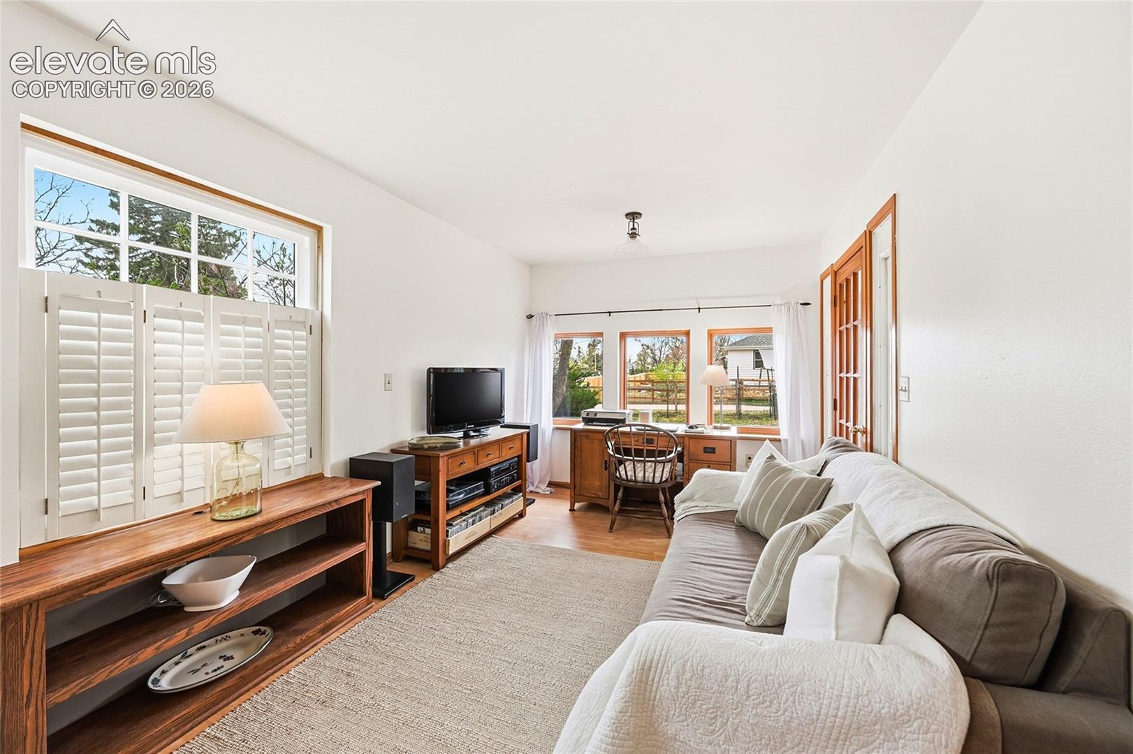 Interior space featuring wood-finish flooring, multi-pane windows, and white plantation shutters