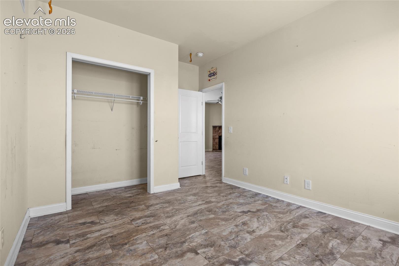 Room featuring neutral wall paint, wood-finish tile flooring, a built-in closet with wire shelving, and a multi-panel interior door