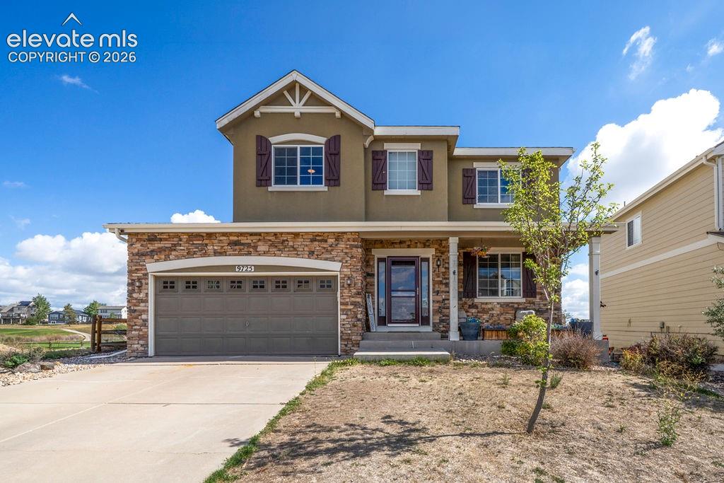 Stucco exterior with stone accents, two-car garage, covered entry, and multiple windows with shutters
