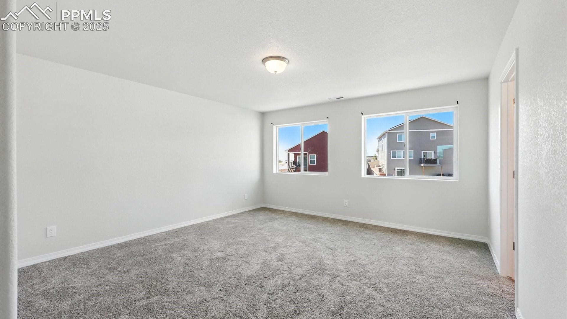 Double doors lead into the Primary Suite with neutral carpet, a walk in closet, and adjoining Bathroom. 
