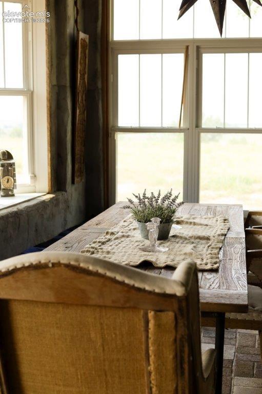 Sunlit dining space featuring a distressed wood table and white-framed casement windows