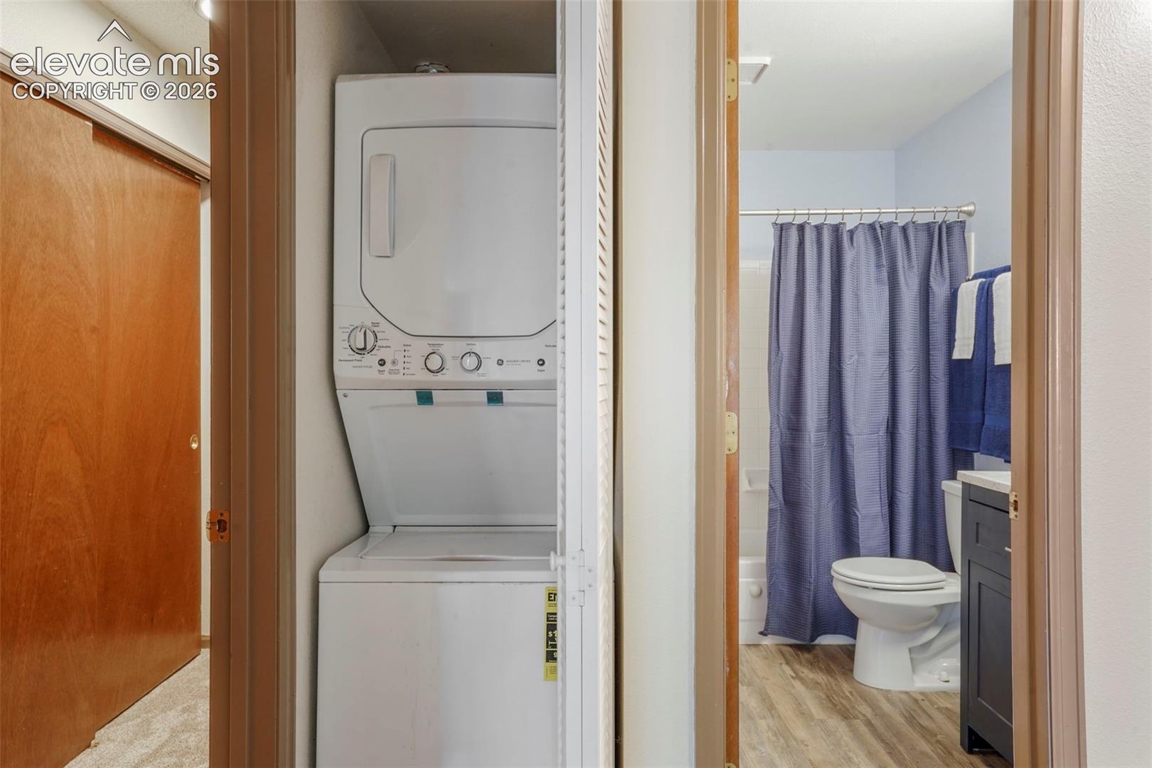 Washroom featuring light wood-type flooring and stacked washing maching and dryer