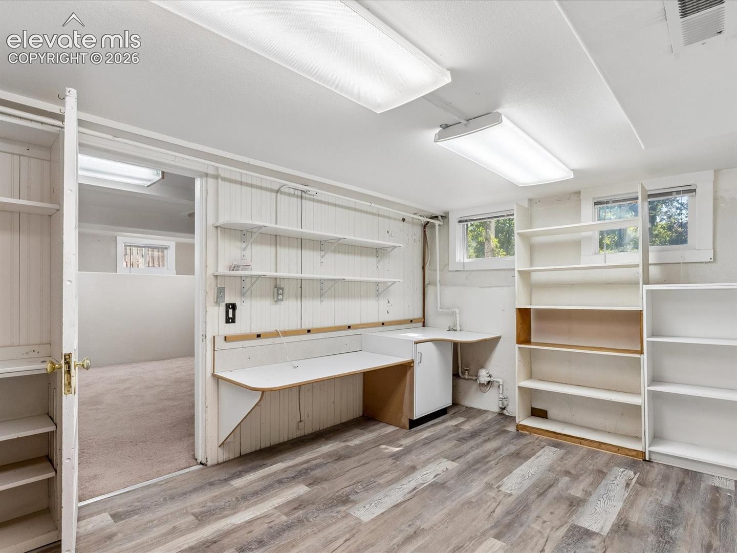 Versatile room featuring wood-finish flooring, built-in shelving, a built-in desk, and multiple windows