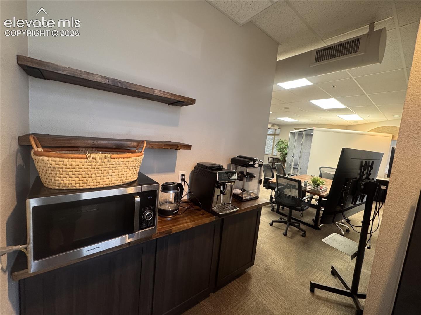 Built-in cabinetry with wood-finish countertop, two wood-finish floating shelves, and stainless steel microwave