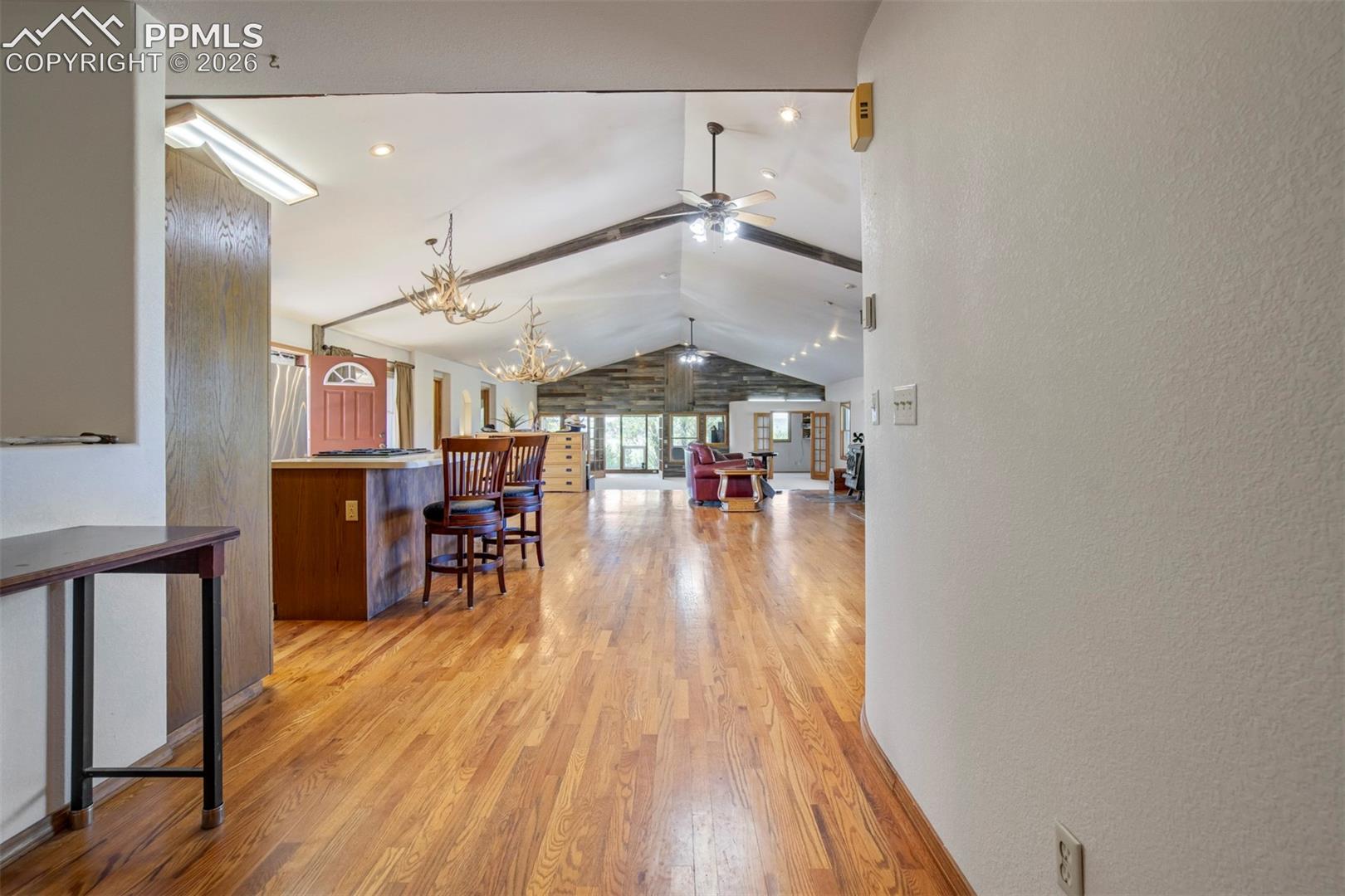 Spacious interior featuring wood-finish flooring, vaulted ceilings with exposed beams, recessed lighting, and ceiling fans