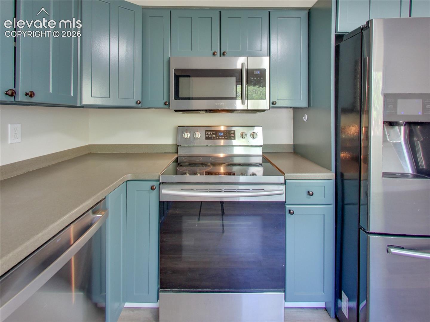 Kitchen featuring blue cabinetry, stainless steel appliances, and solid surface countertops