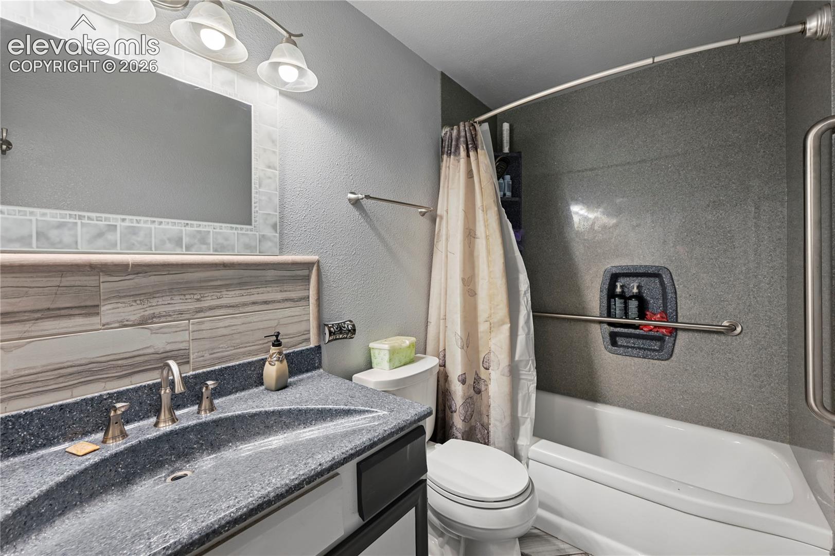 Main Bathroom featuring a built-in tub and shower combination with a curved shower rod and grab bars