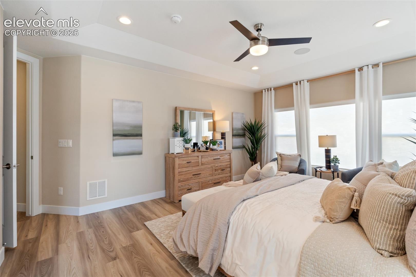 Tray ceiling featuring recessed lighting, expansive wood-finish flooring, and a modern ceiling fan with integrated light fixture