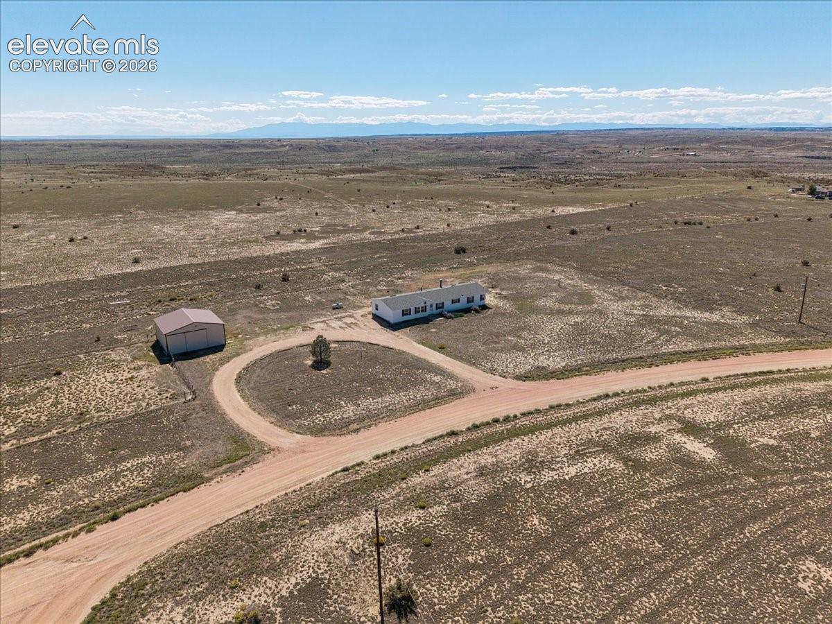 Extensive open acreage with a primary residence, a large outbuilding, and a circular drive