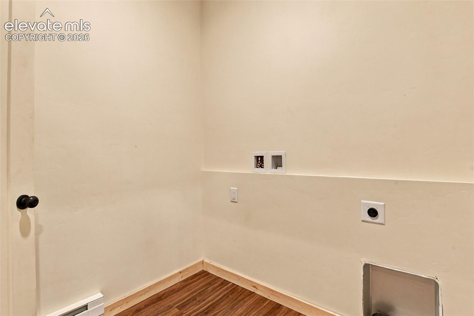 Utility area featuring wood-finish flooring, dedicated water hookups, electrical outlet, and an exhaust vent