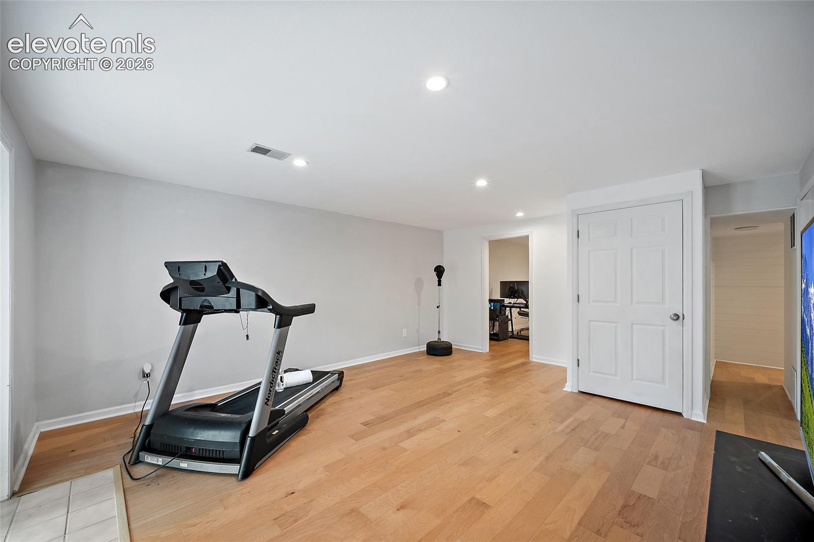 Interior space featuring light wood-finish flooring, recessed lighting, and a six-panel door