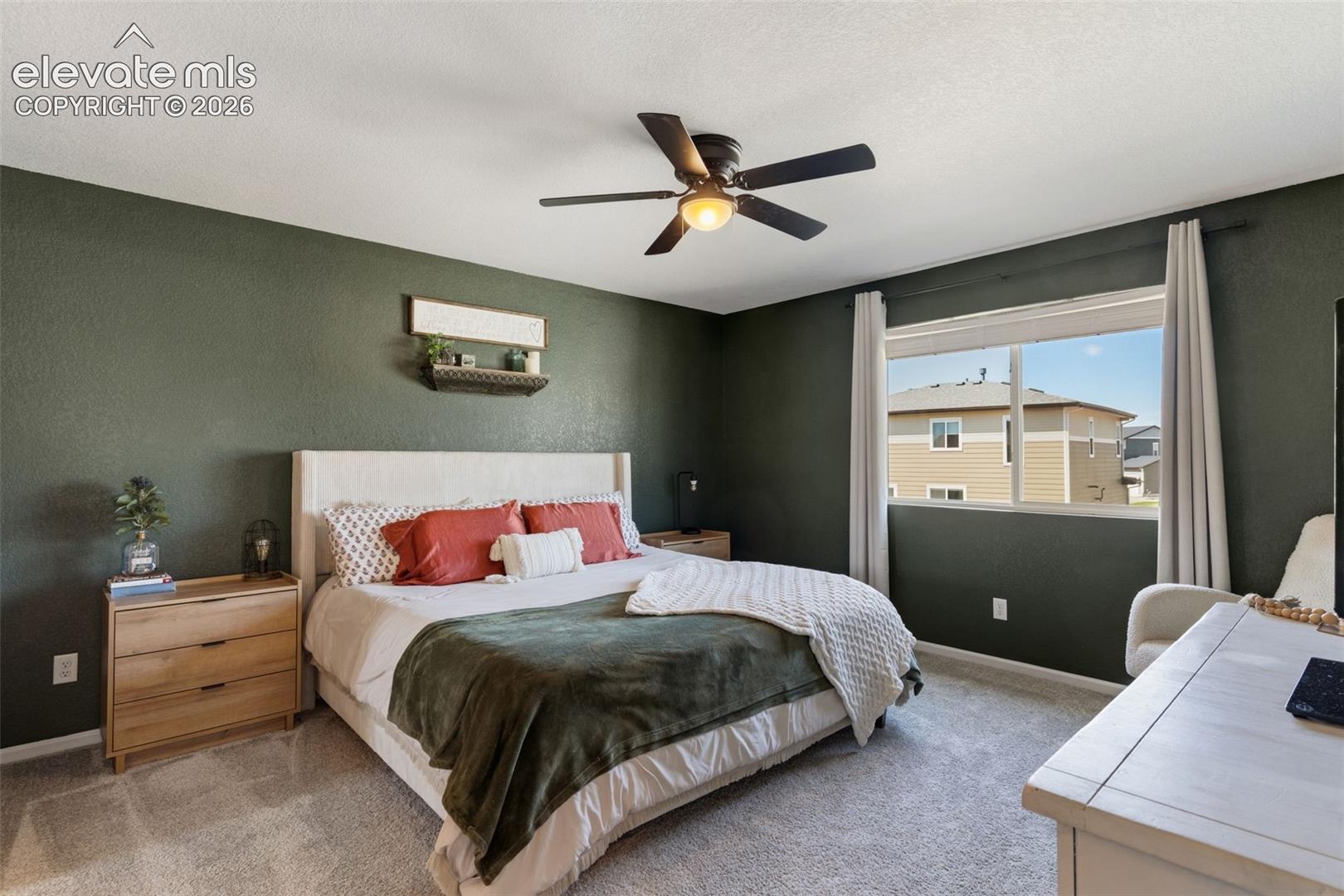 Bedroom featuring dark green walls, a single window, and a ceiling fan with integrated lighting