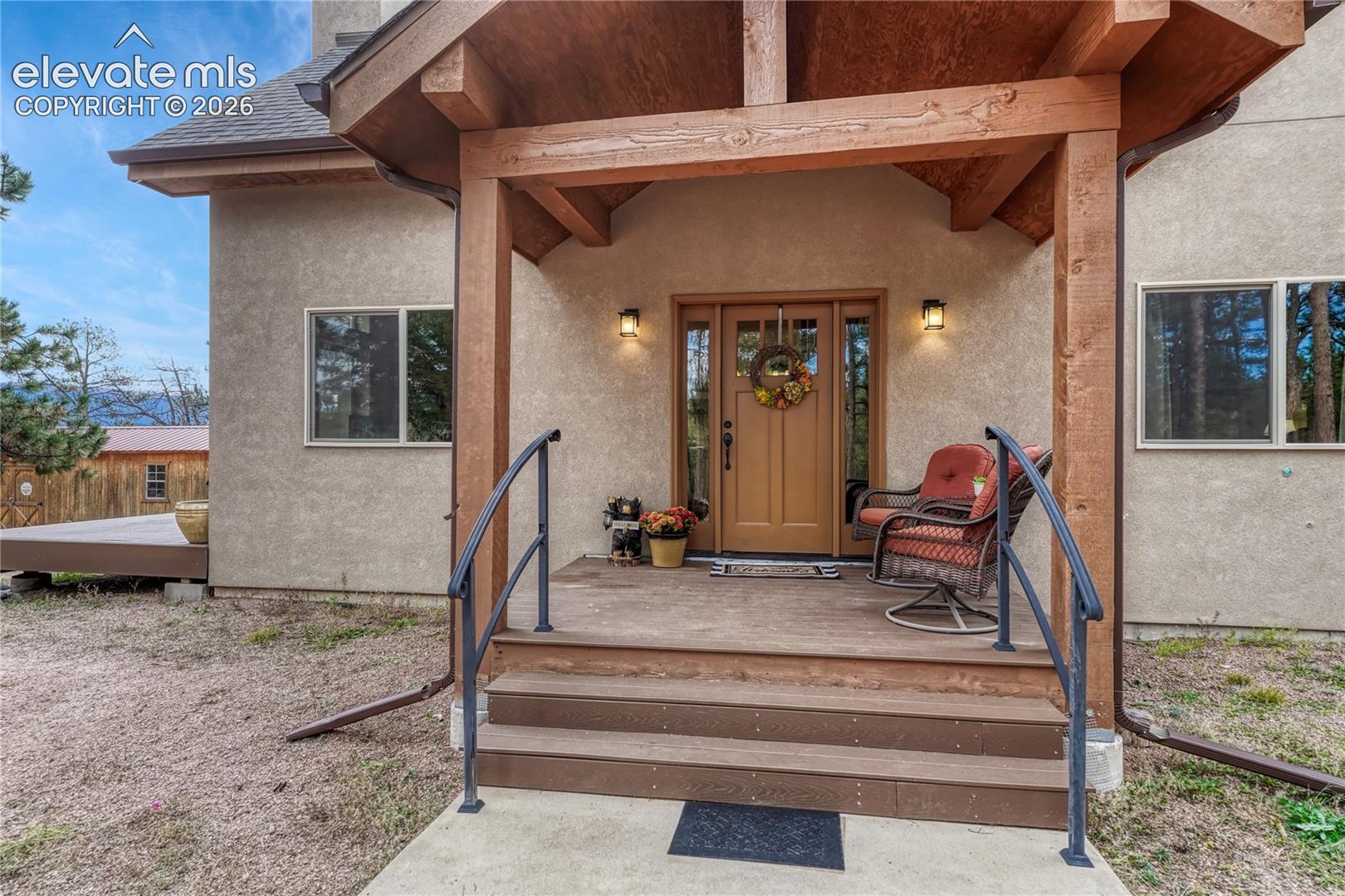 Covered entrance featuring timber-frame accents, exterior stucco finish
