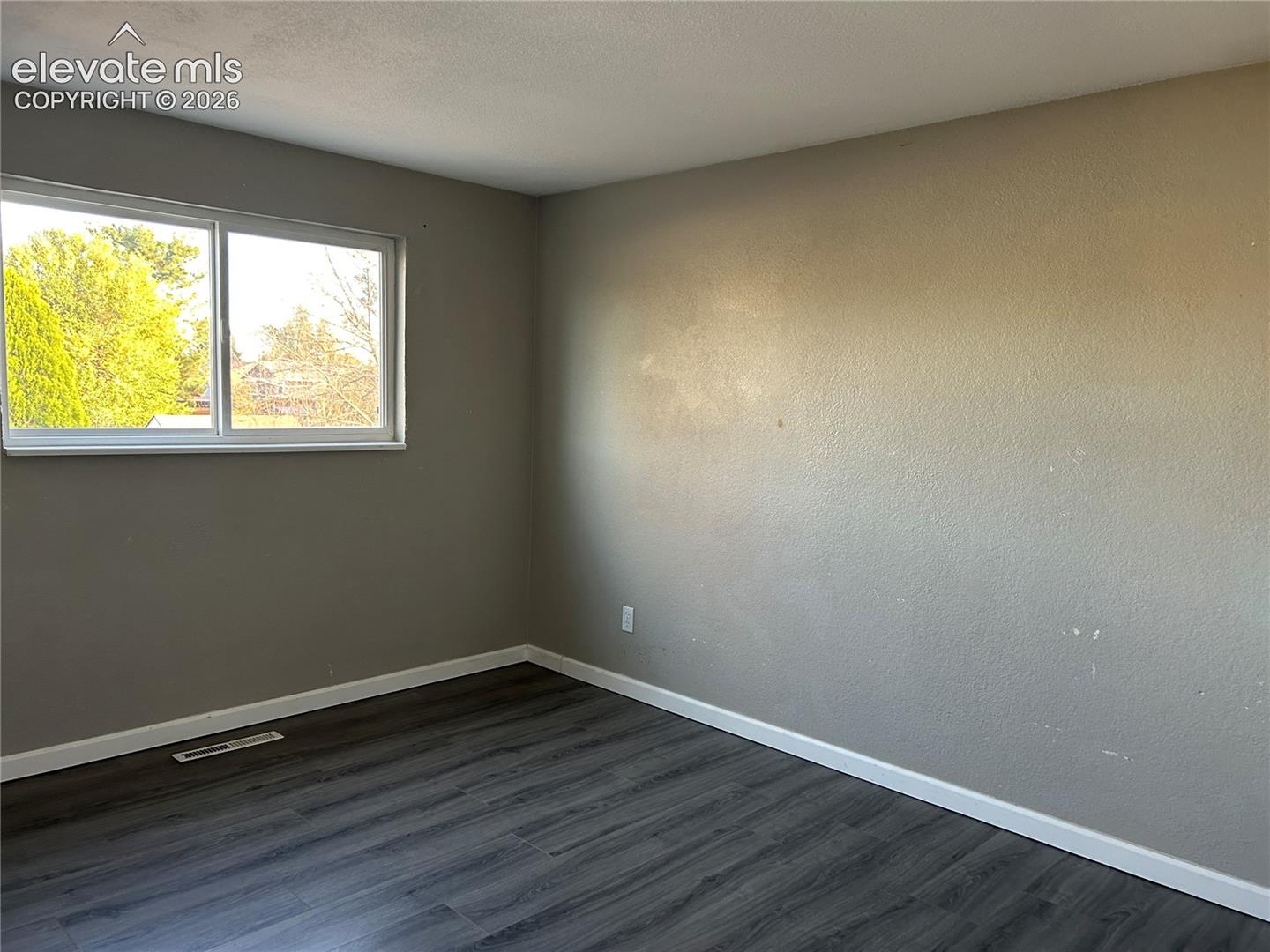 Neutral-toned interior space featuring wood-finish flooring and a dual-pane sliding window