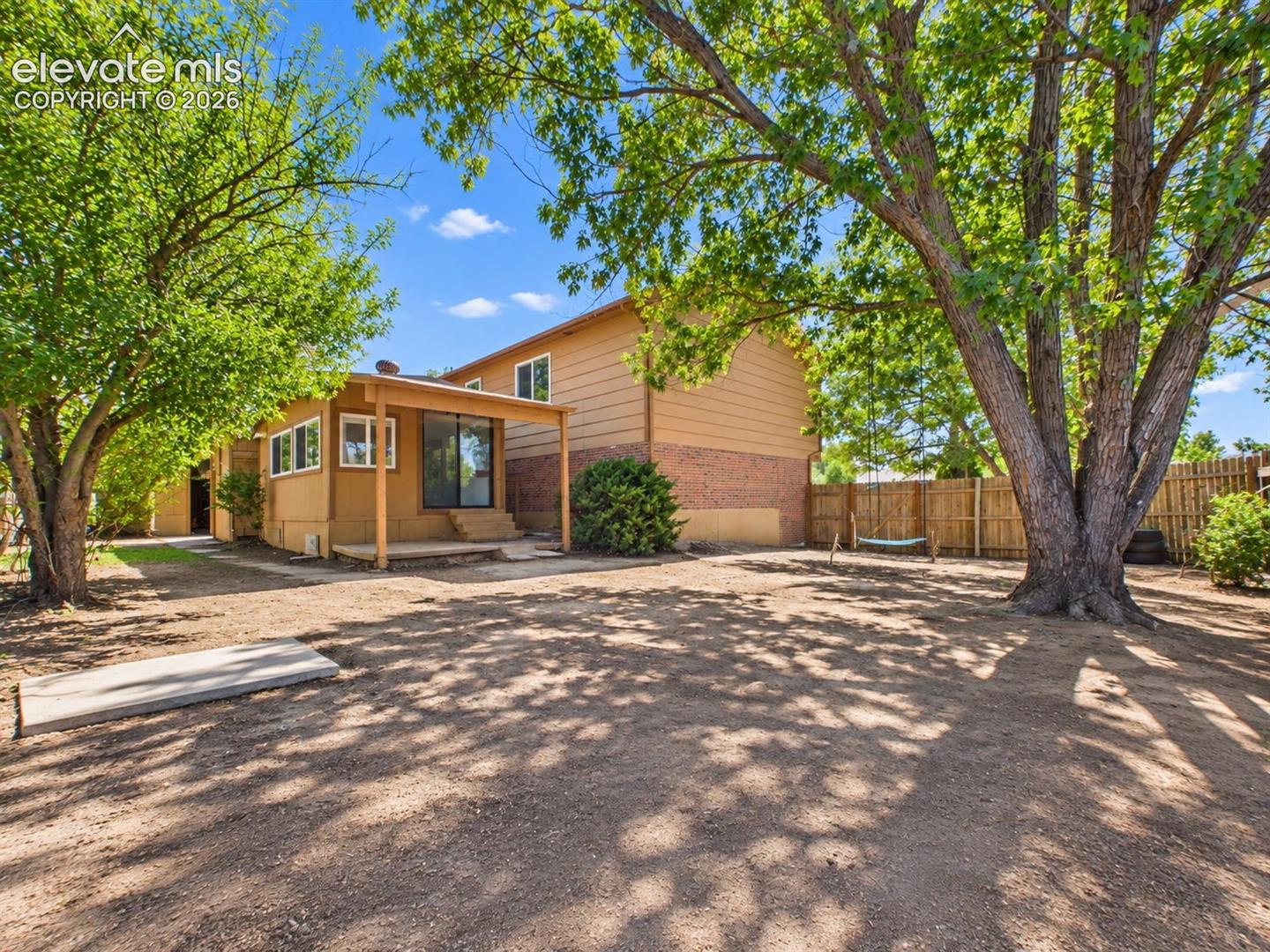 Spacious fenced backyard is shaded by mature trees and includes an outdoor seating area with plenty of room for additional landscaping or recreation.