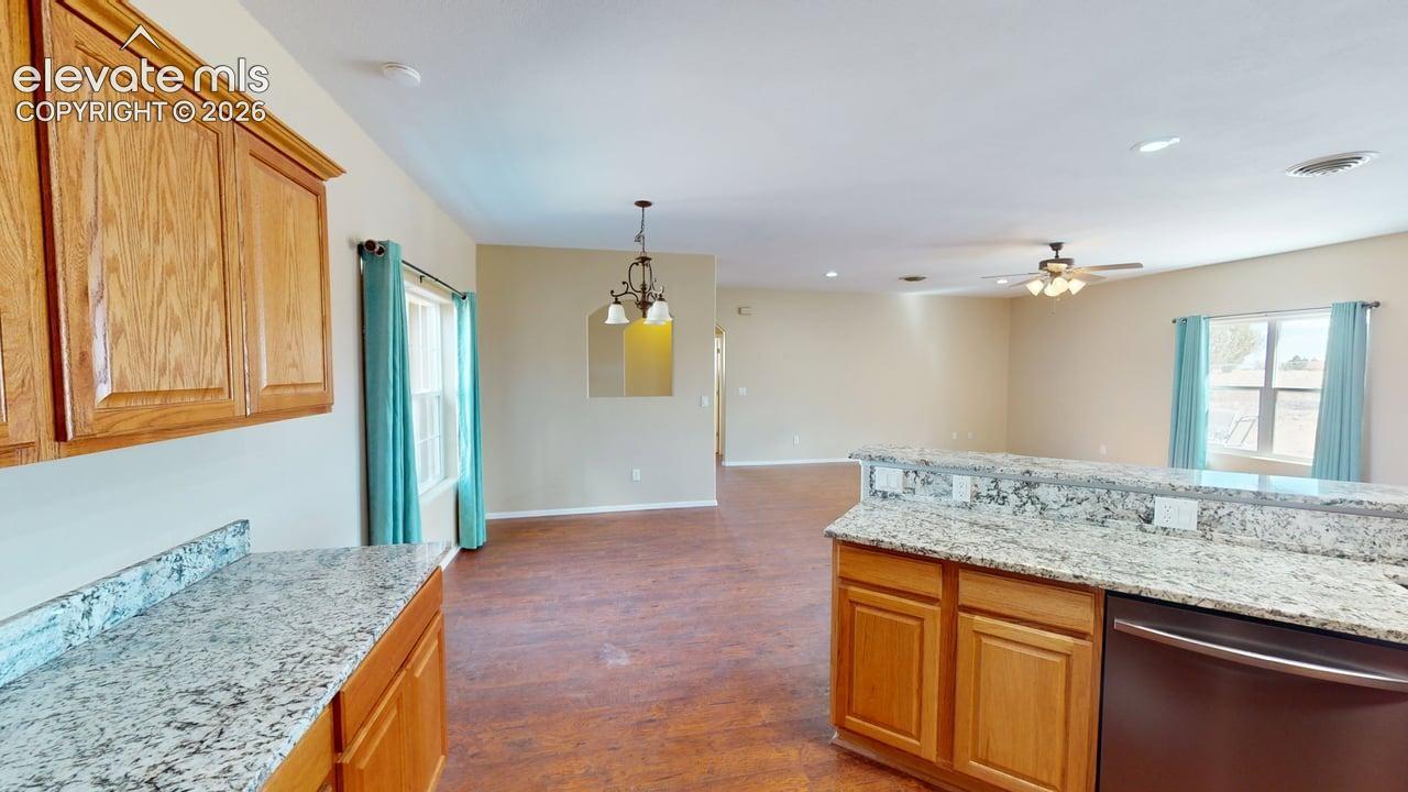 Wood-finish flooring throughout, with light-toned wall paint, and kitchen featuring wood cabinetry and granite-style countertops