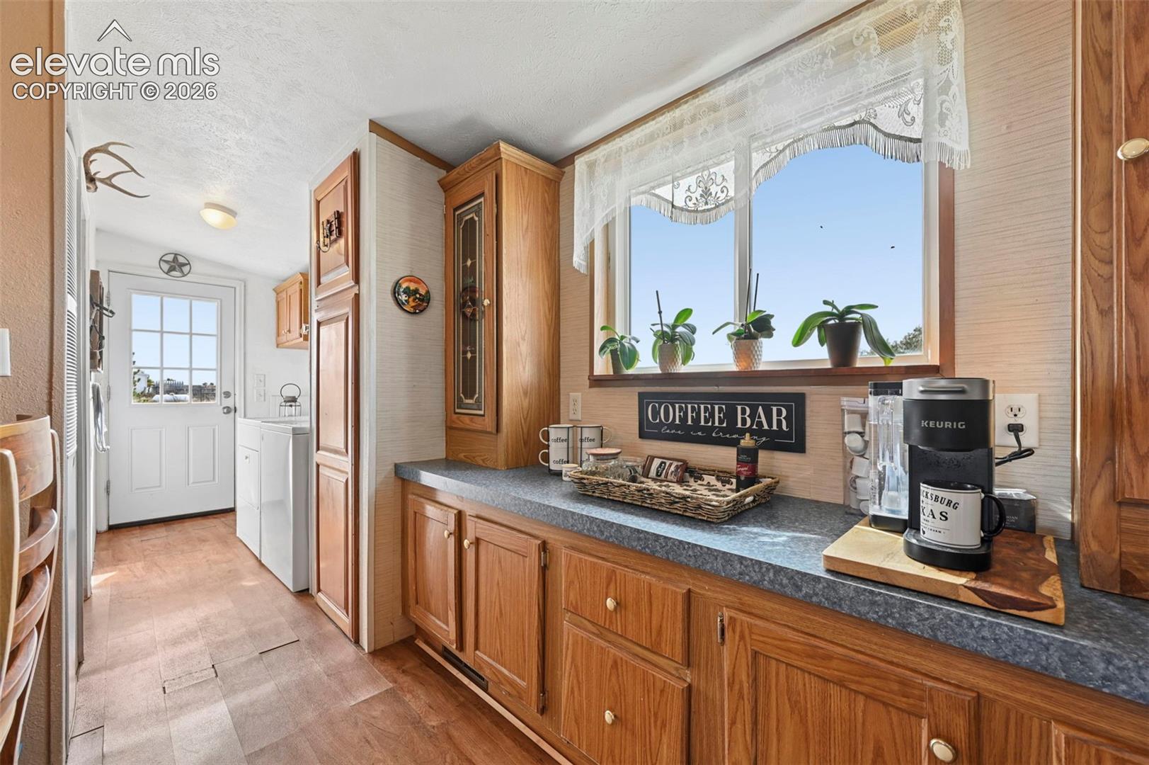 Kitchen featuring natural wood-finish cabinetry, solid-surface countertops, a built-in display hutch, and a large window above the prep area