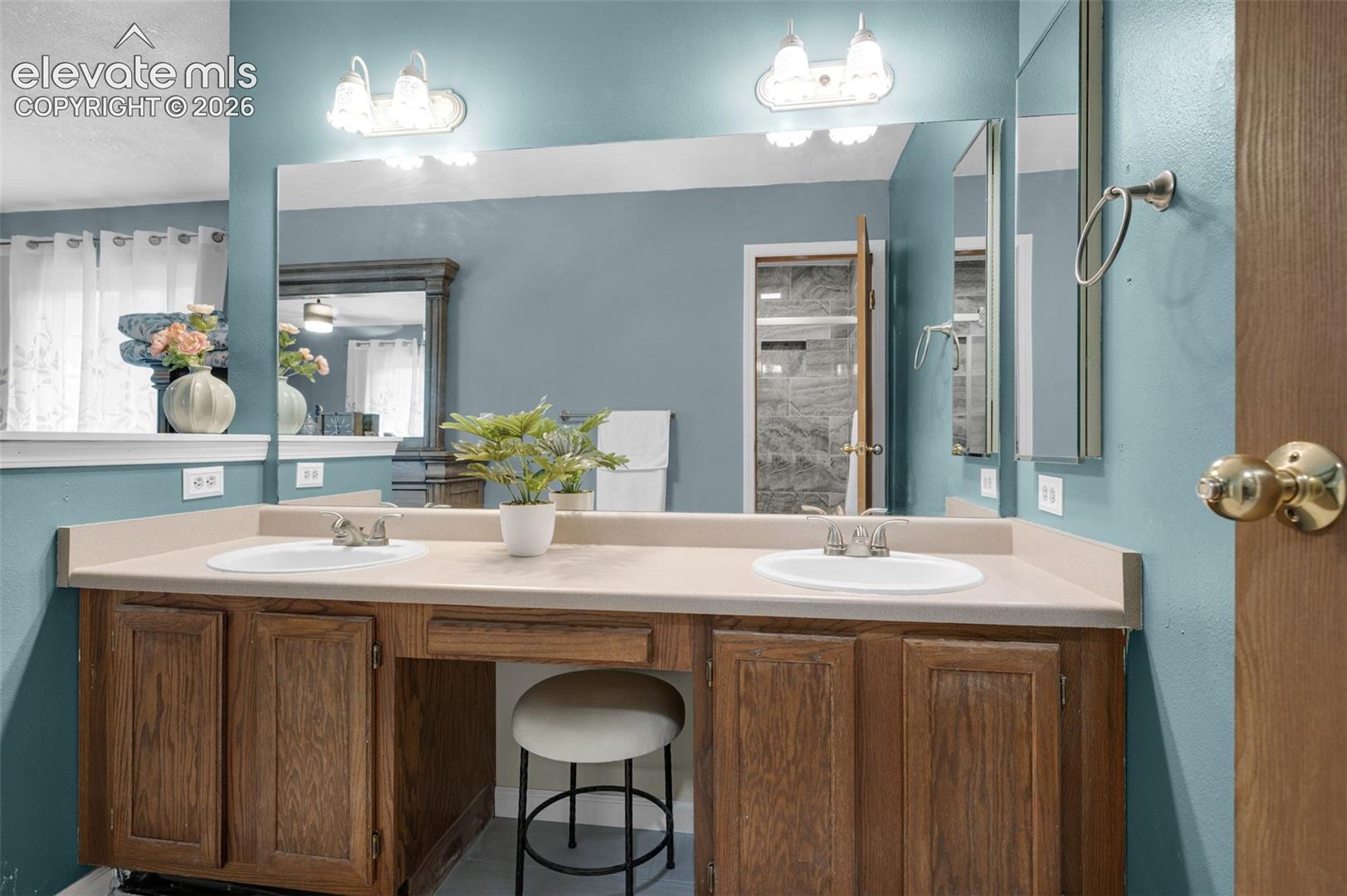 Double vanity with integrated sinks, a spacious countertop, wood cabinetry, and a dedicated vanity seating area