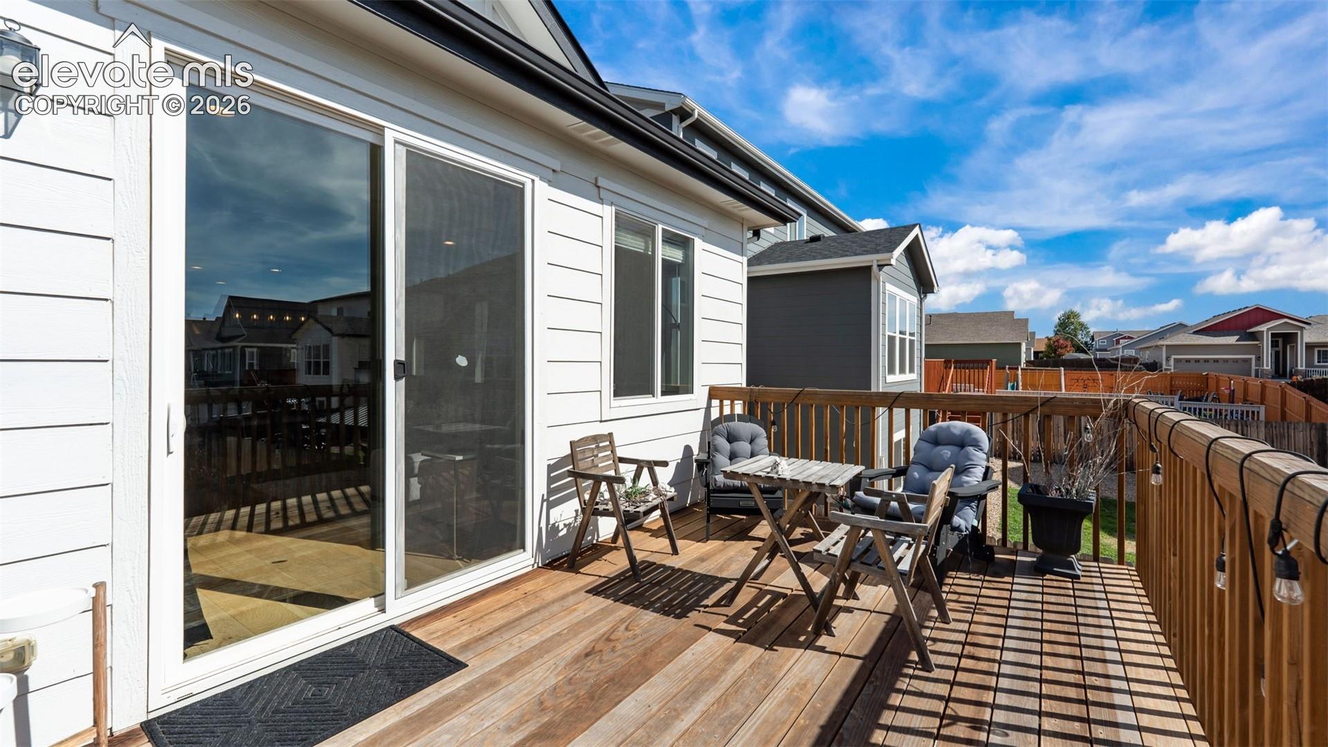 Expansive wood-plank deck with a full railing, white horizontal siding, and large sliding glass door