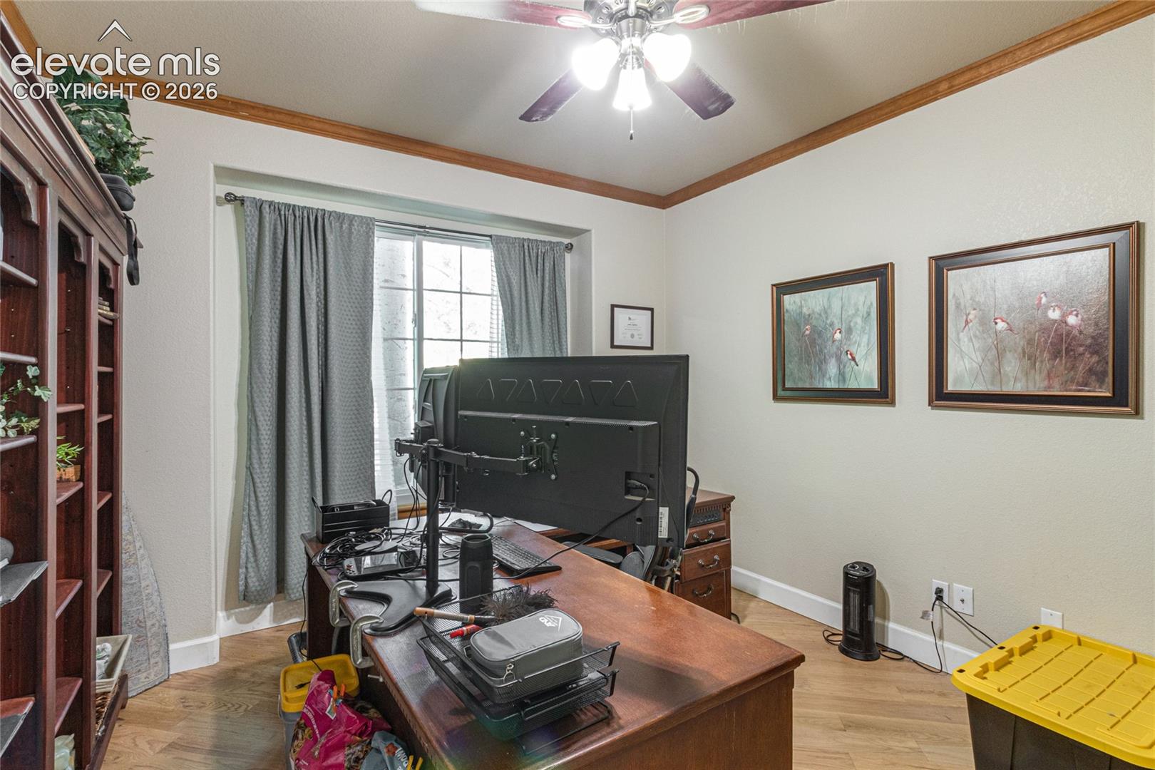 Wood-finish flooring, ceiling fan with integrated lighting, built-in wooden shelving, and window with multi-pane grid detailing