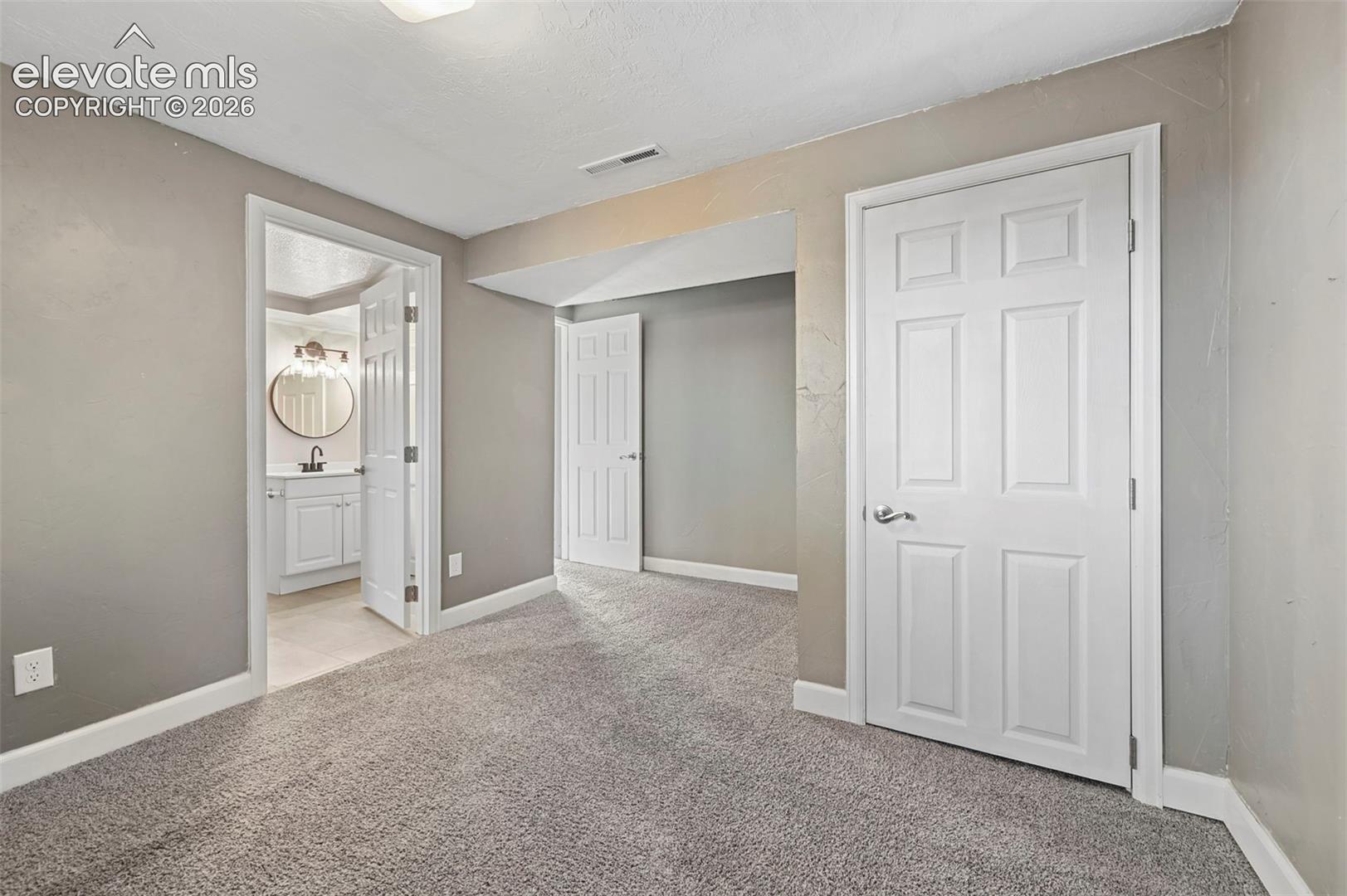 4th bedroom in basement level, with ensuite is a perfect place for guests!   Interior space featuring neutral-toned walls, wall-to-wall carpeting, and six-panel interior doors