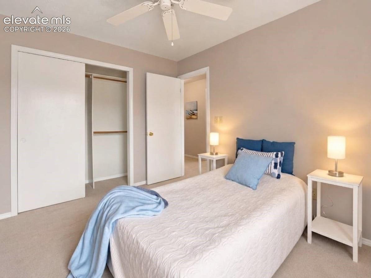 Neutral-toned interior featuring wall-to-wall carpeting, ceiling fan with integrated lighting, and a closet with sliding doors