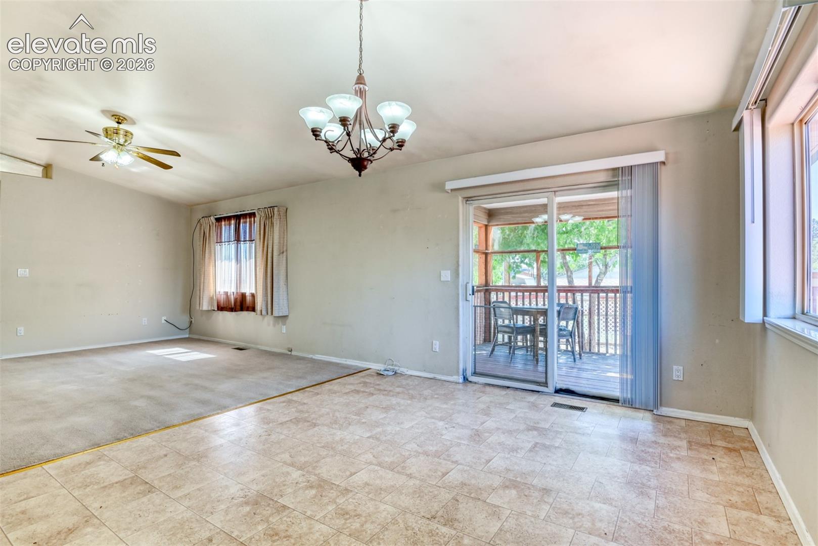 Living area featuring ceramic tile flooring, a multi-arm chandelier, ceiling fan, and sliding glass doors with access to an exterior deck
