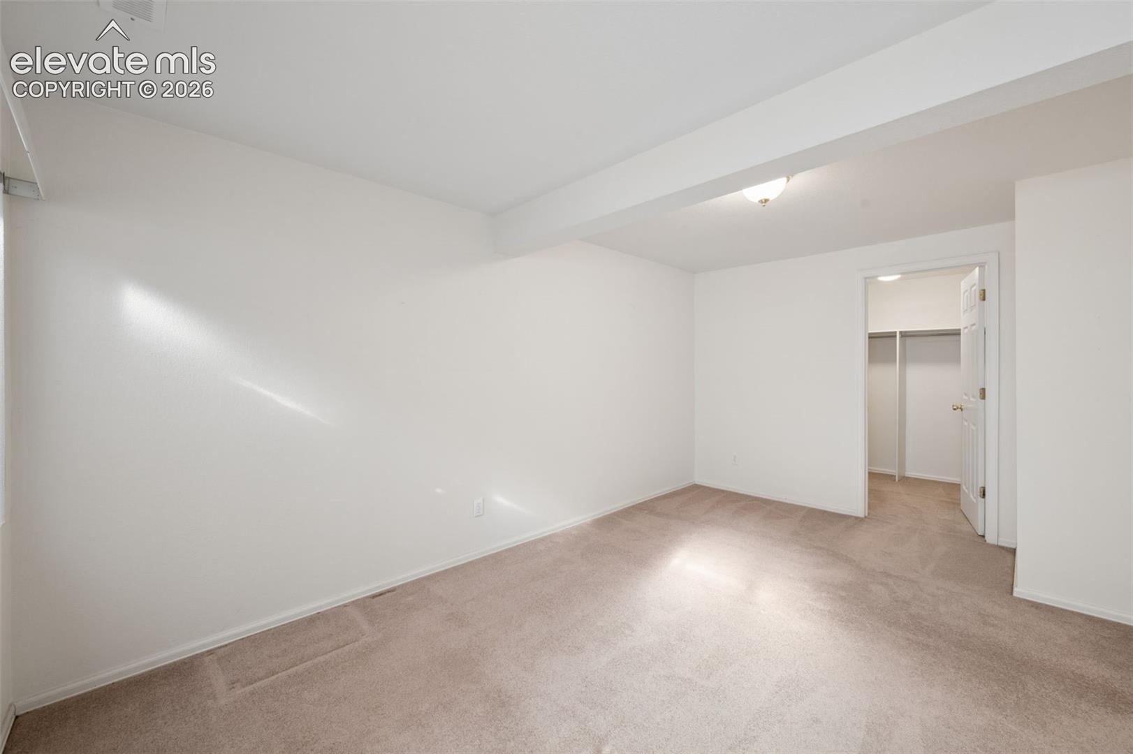 Neutral-toned wall-to-wall carpeting, crisp white wall finishes, and a walk-in closet featuring built-in shelving