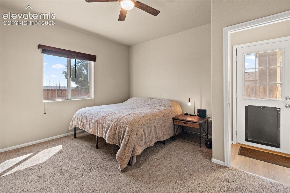 Carpeted room featuring a ceiling fan, window with blinds, and an exterior door with glass inserts and a pet door