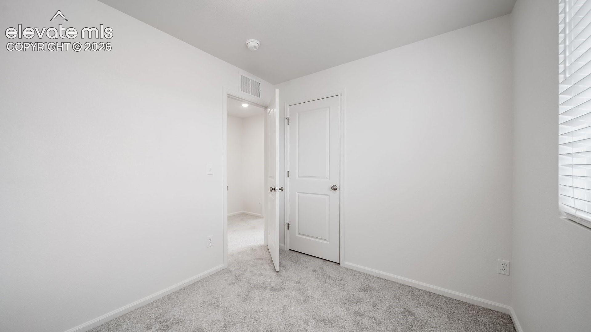 Light-toned carpeting, white painted walls, and a white interior door
*photos of a model home*