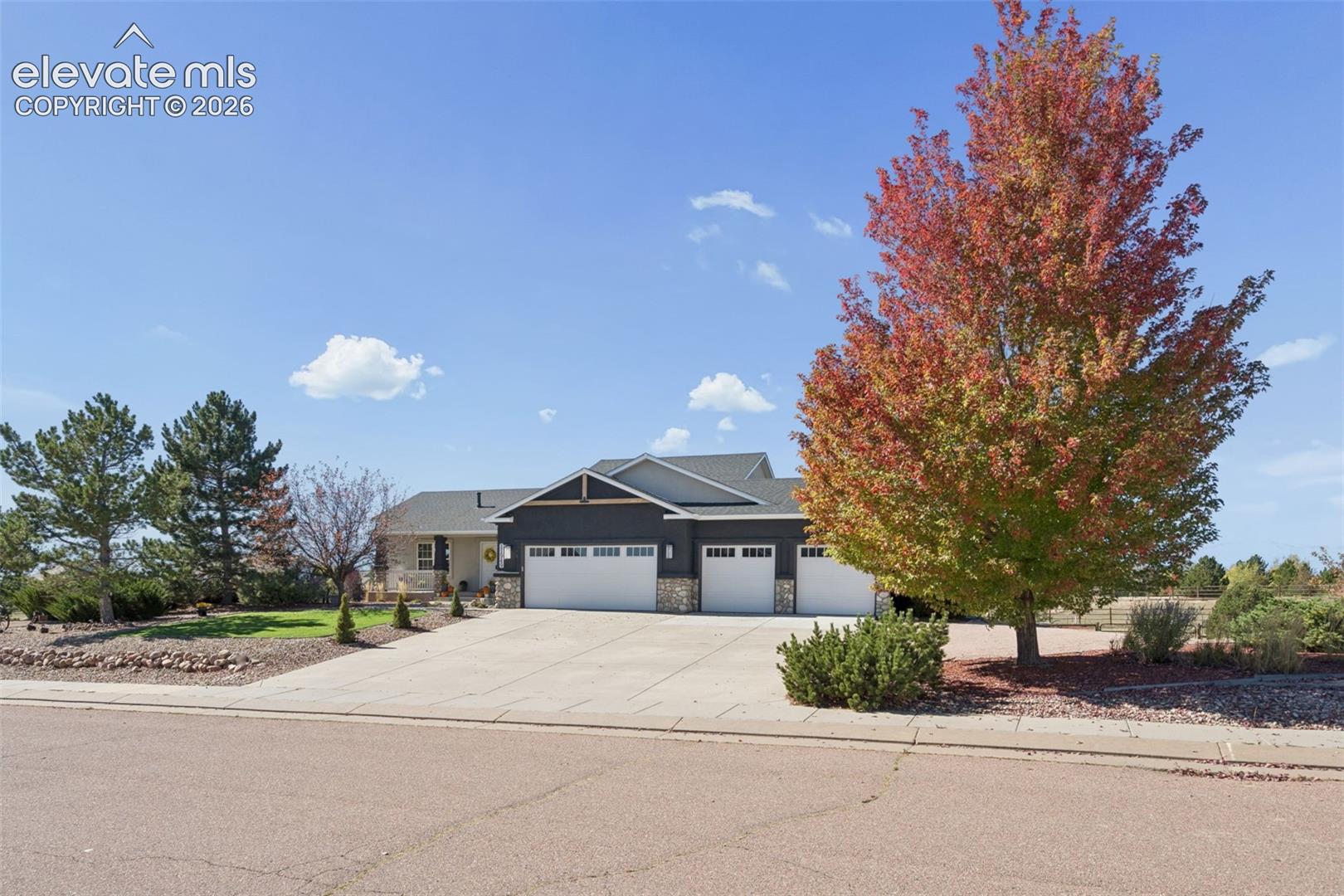 Attached three-car garage with white doors, dark siding, and stone accents